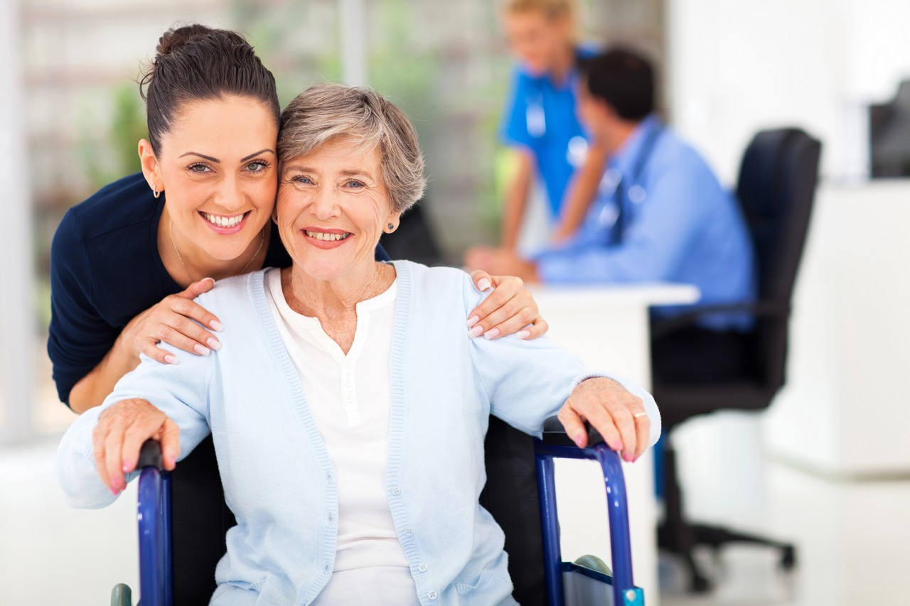 Carer warmly embracing an elderly woman in a wheelchair at a clinical care facility